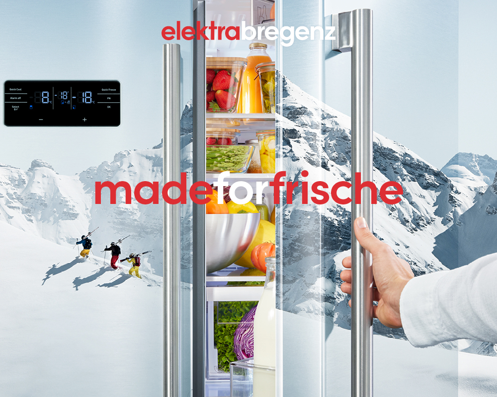 Alpine Gebirgslandschaft mit 3 Ski-Fahrer:innen stampfend durch den Schnee auf einem Ausschnitt einer geöffneten Kühlschranktür projiziert. Logo elektrabregenz und Claim „madeforfrische“ 